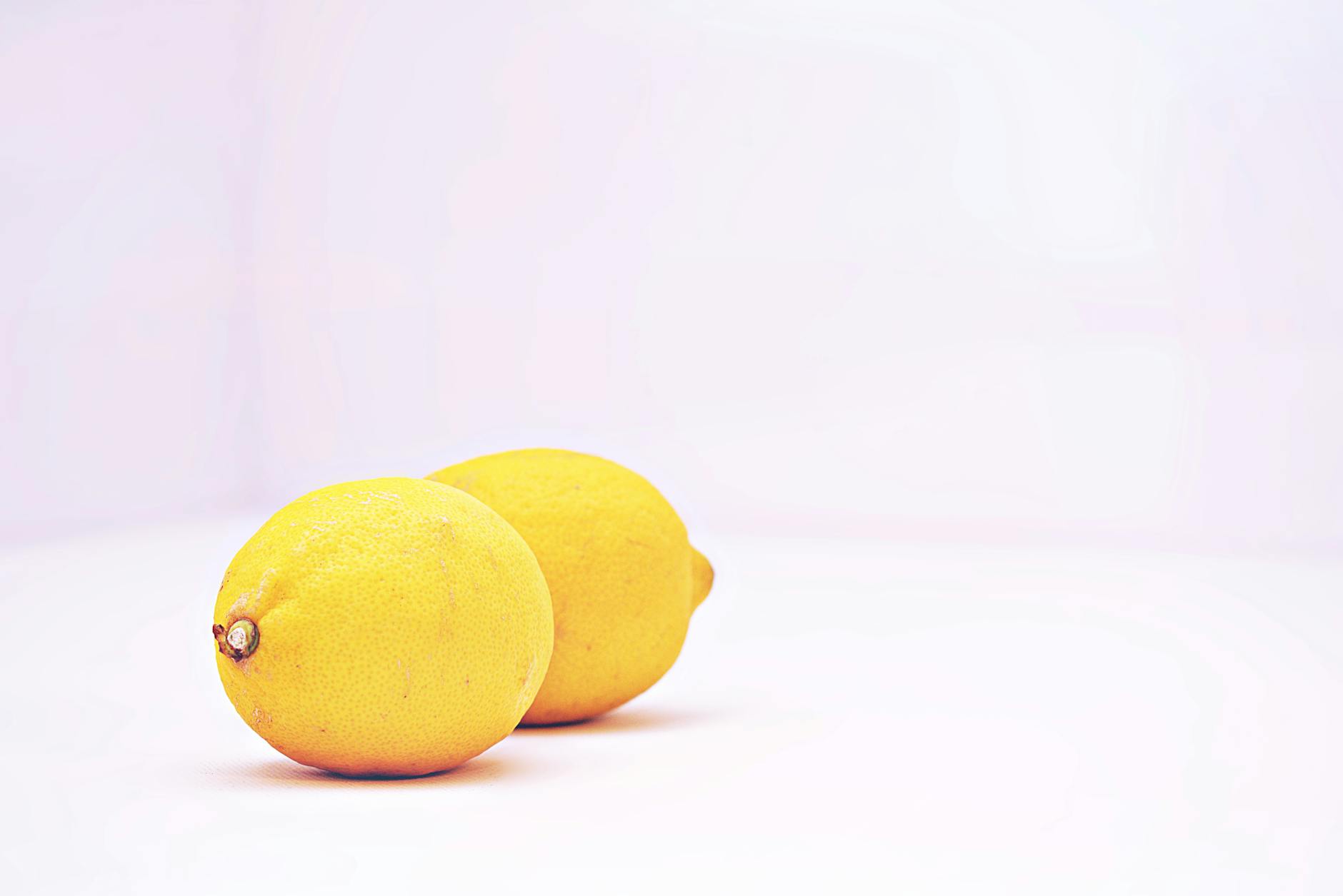 Blue vibrator surrounded by flowers and citrus slices on a yellow background
