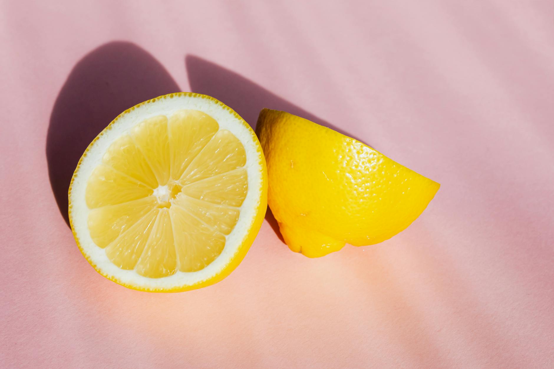Fresh lemon halves on a pink background in warm sunlight