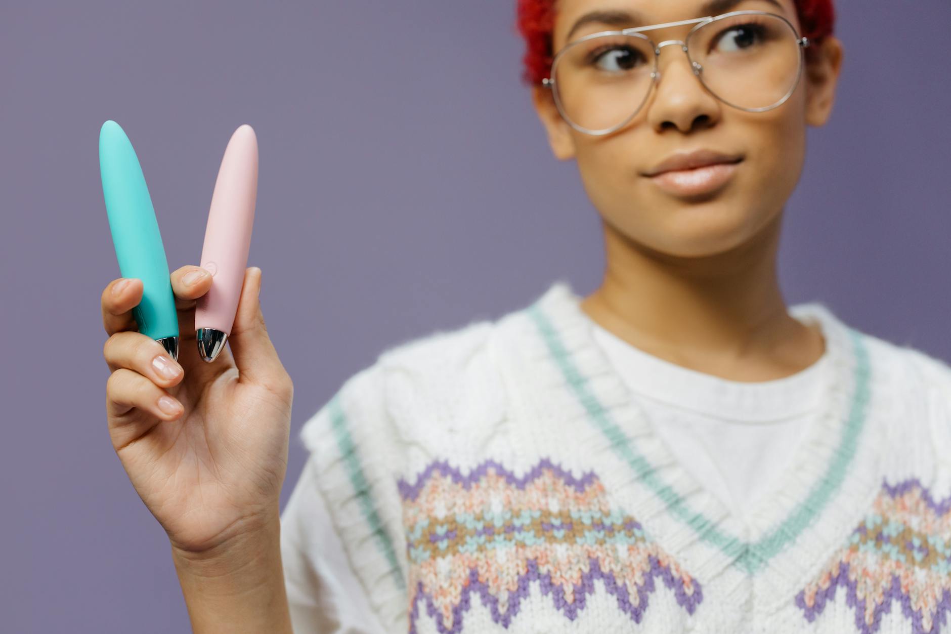 A hand holding a blue silicone vibrator against a purple background, symbolizing self-love and personal pleasure.