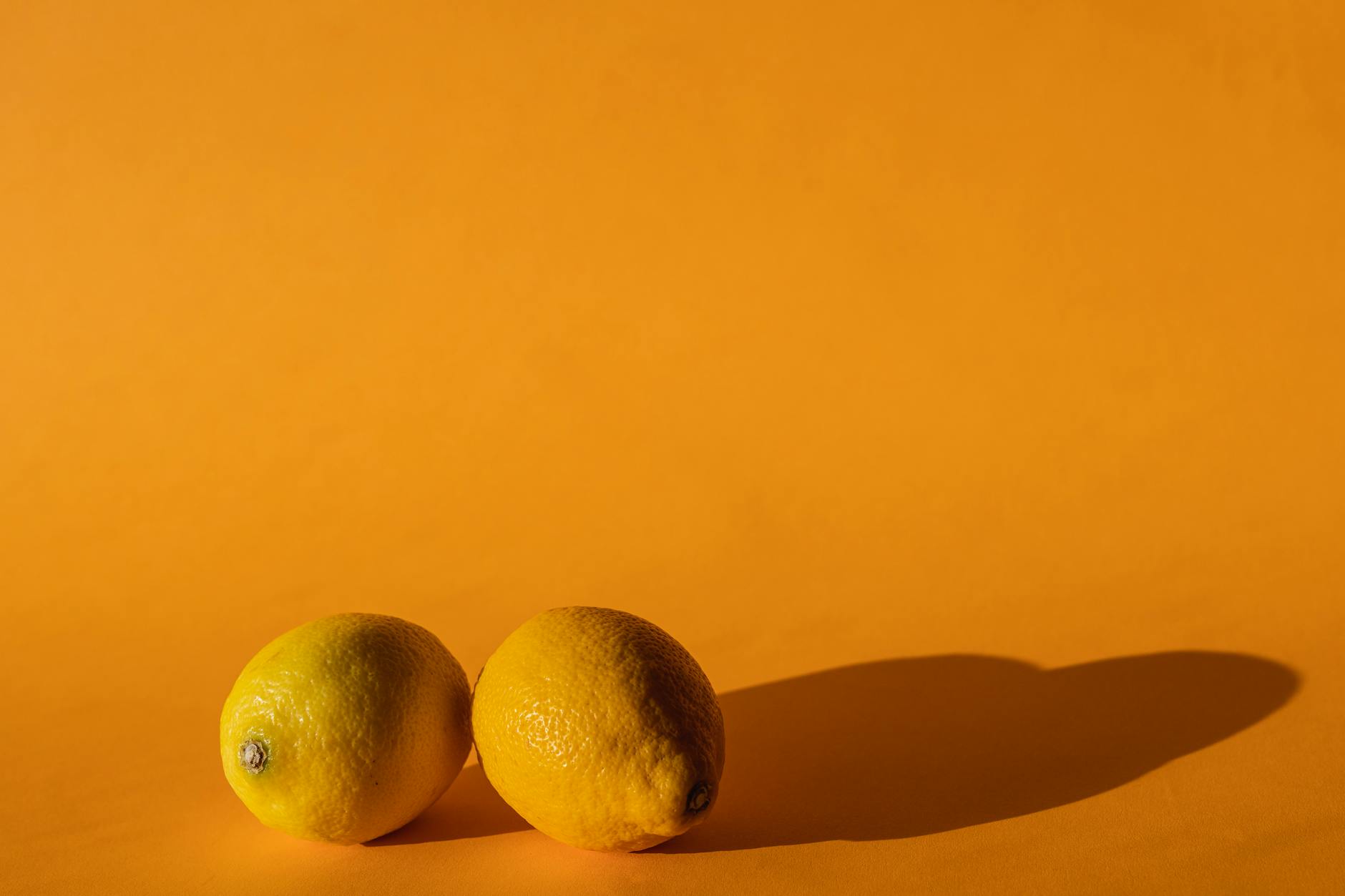 Fresh lemons arranged on a bright yellow background, symbolizing the Lemon vibrator brand